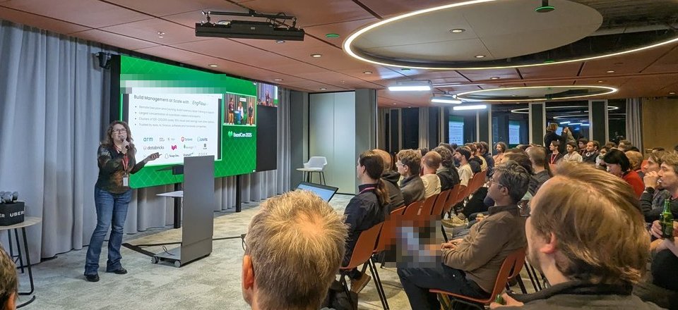 The EngFlow speaker presenting the Build Management at Scale with EngFlow slide, with BazelCon 2025 branding and customer logos, to a full room at Uber Amsterdam