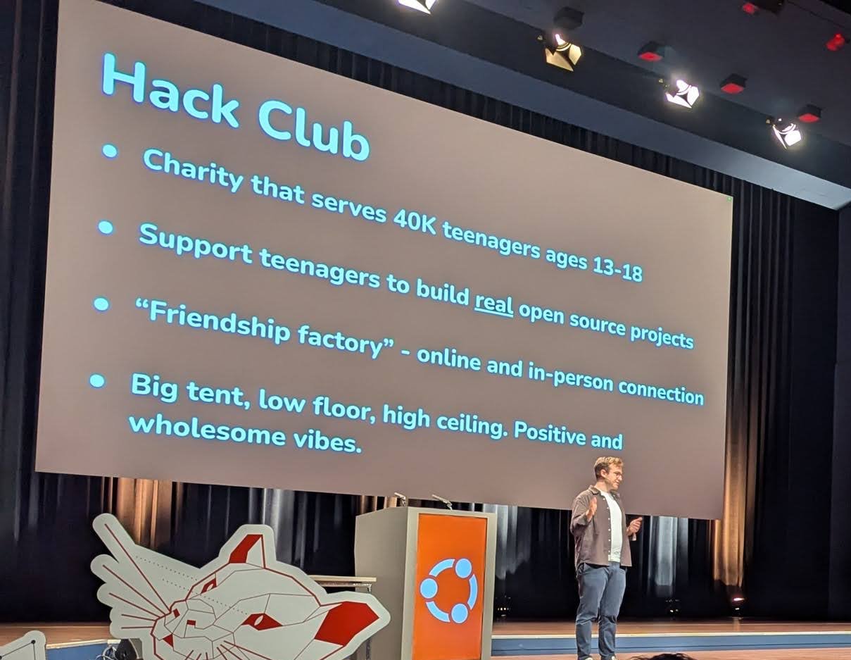Hack Club slide at Ubuntu Summit 2024 reading charity that serves 40K teenagers ages 13-18, support teenagers to build real open source projects, with the speaker on stage