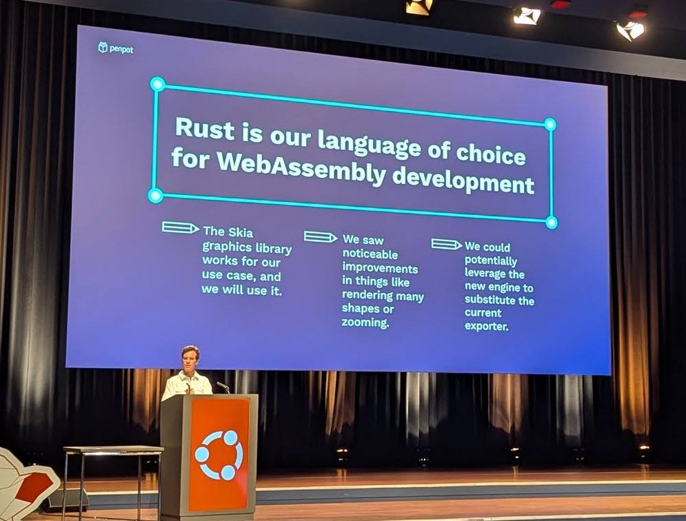 Pablo Ruiz-MĂșzquiz at the podium under a Penpot slide reading Rust is our language of choice for WebAssembly development, with notes on the Skia graphics library