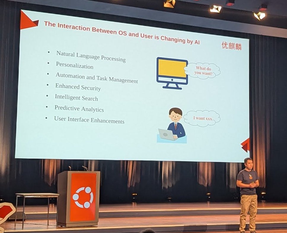 Ubuntu Kylin speaker on stage with the slide The Interaction Between OS and User is Changing by AI, listing natural language processing, personalisation and automation