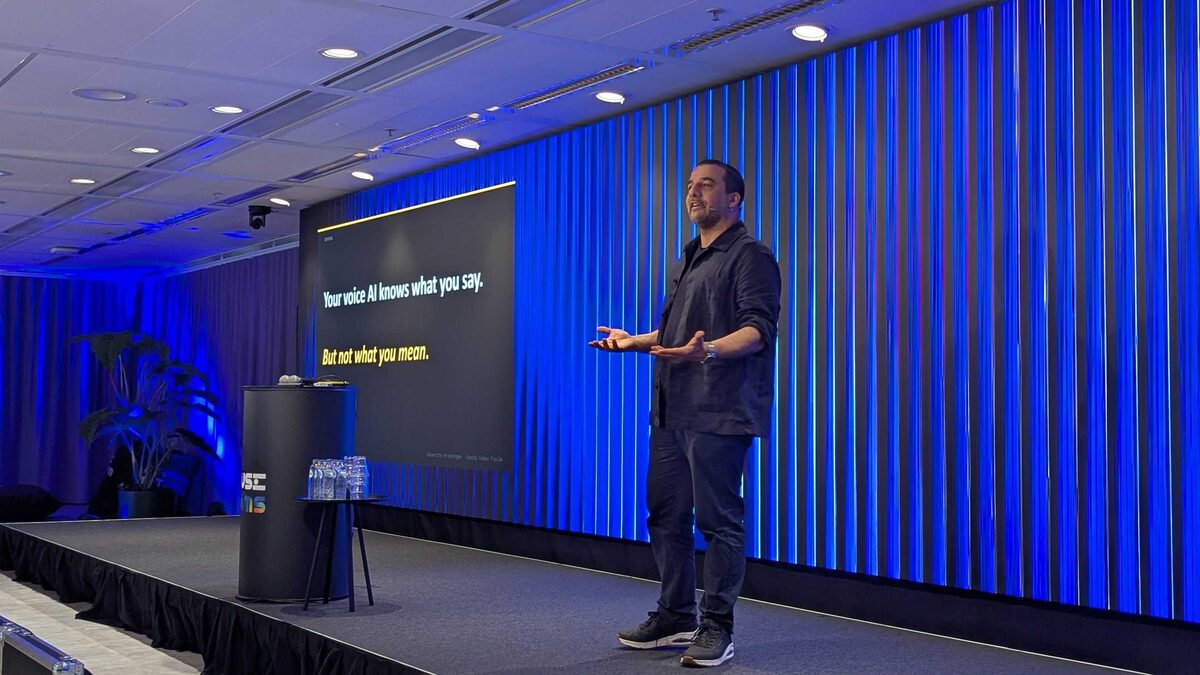 Wide shot of Matt Coler on the full stage with dual-screen setup