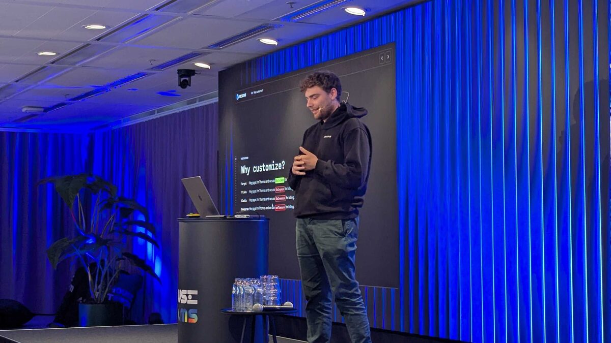Thomas on stage at Voice AI Space — presenting the customization problem with blue stage lighting
