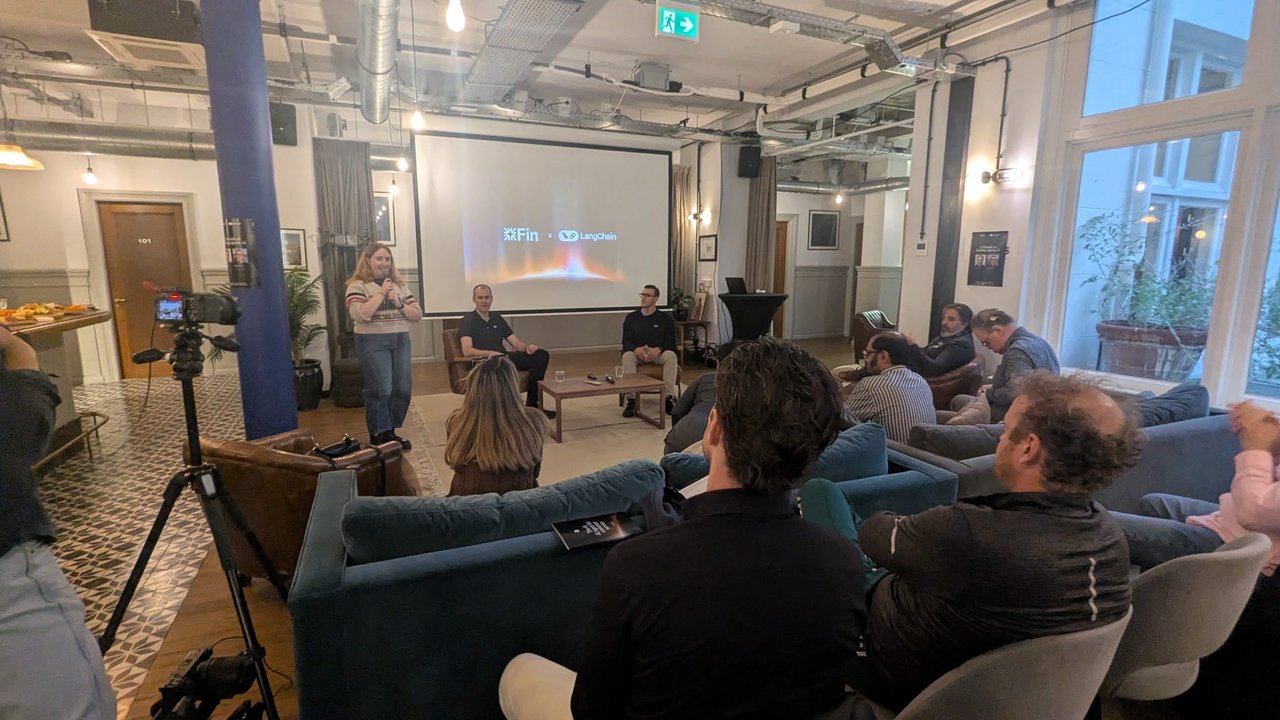 The Fin and LangChain fireside on building agentic AI: two speakers in armchairs and a host in front of a projector showing the Fin and LangChain logos