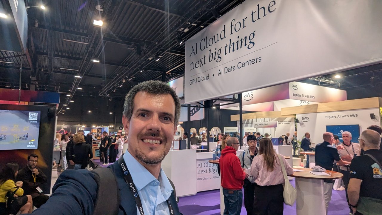 Luca Berton smiling in the busy World Summit AI expo hall, under a large sign reading AI Cloud for the next big thing, GPU Cloud and AI Data Centers