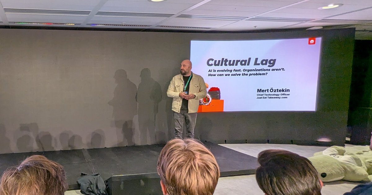 Mert Öztekin on stage at Agents in Production, AI House Amsterdam, next to his Cultural Lag title slide naming him Chief Technology Officer of Just Eat Takeaway.com