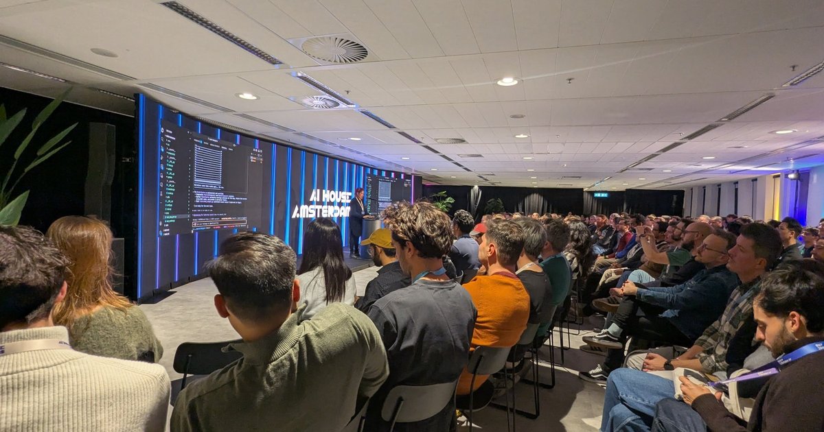 A packed AI House Amsterdam auditorium during the Google coding assistants session, with a terminal demo on the big screens