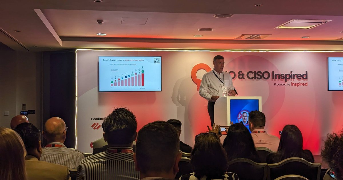 Speaker at the podium on the CIO & CISO Inspired stage, with a slide about GenAI reaching 100 million users on the screen