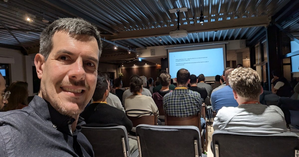 Luca Berton in the audience at the Cloudflare Founders & Developers Meetup in Amsterdam, with a talk on the screen behind him
