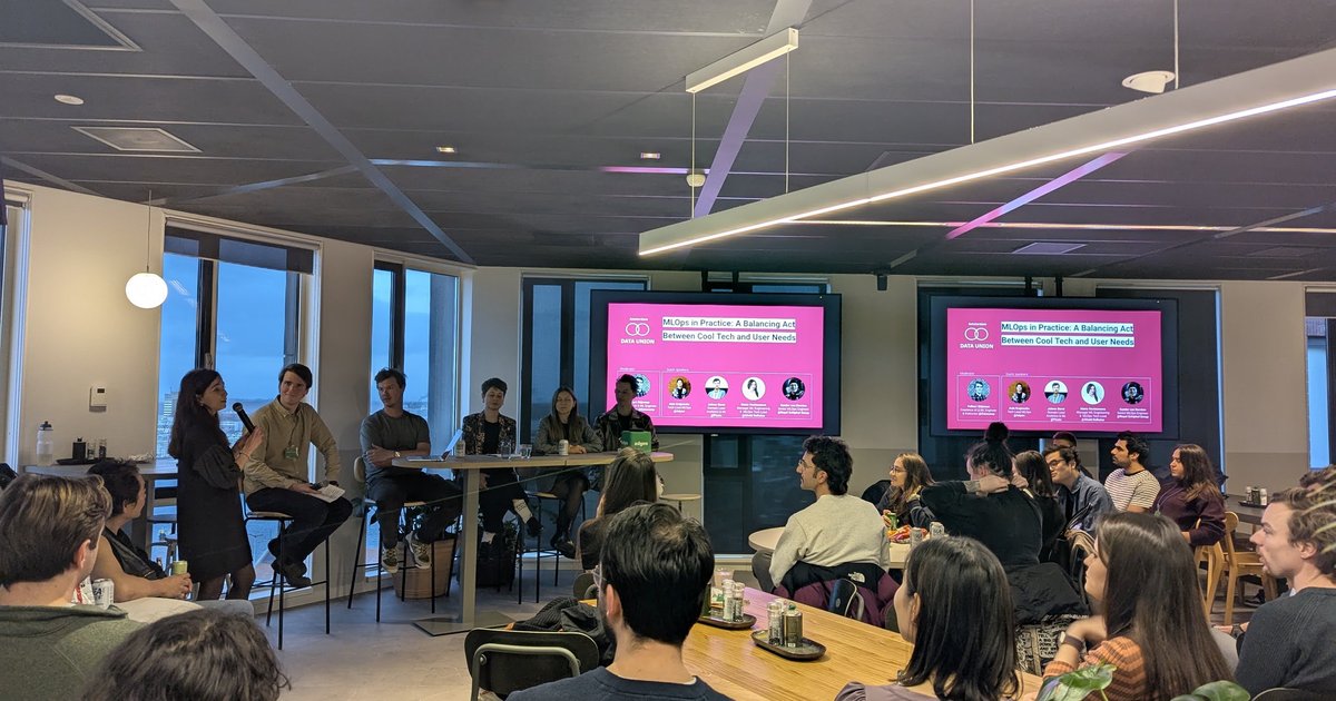 Data Union Amsterdam MLOps in Practice panel with five people on stage and the pink title slide on two screens