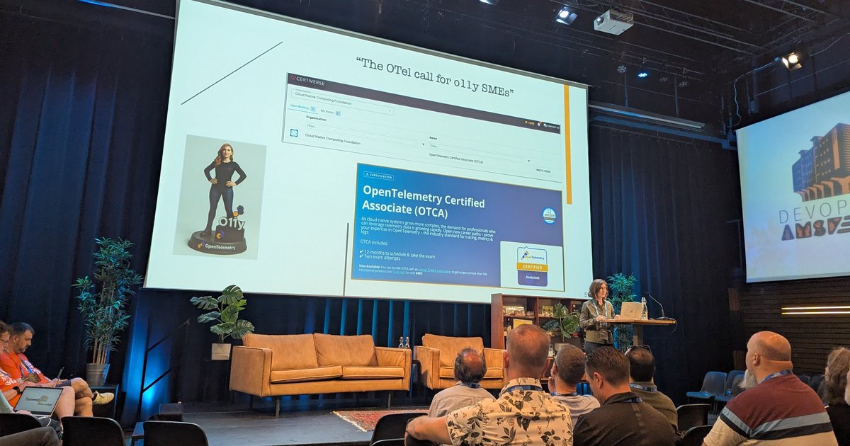 A speaker on stage at DevOpsDays Amsterdam 2025 in front of a slide titled The OTel call for o11y SMEs