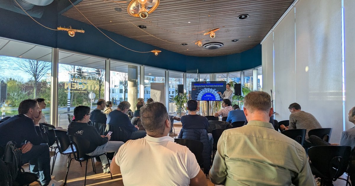 Attendees seated in a glass-walled room at Nutanix in Hoofddorp facing a screen during the KubeCon EU recap meetup