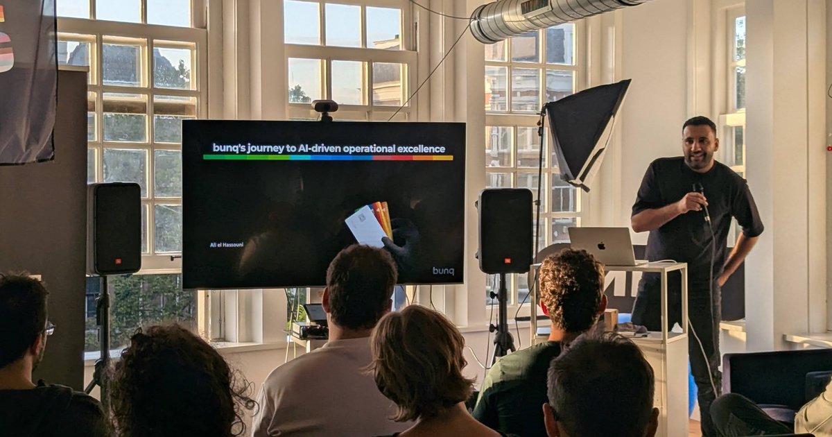 Ali el Hassouni of bunq on stage next to the title slide bunq's journey to AI-driven operational excellence at the Google Cloud User Group Amsterdam