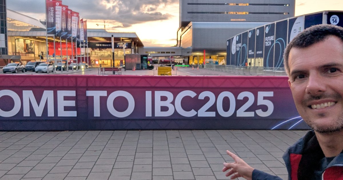 Luca Berton pointing at a large Welcome to IBC2025 banner outside the RAI Amsterdam halls at sunset