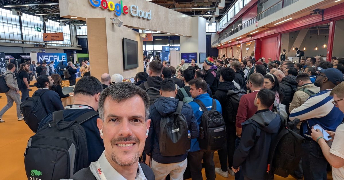 Luca Berton taking a selfie on a crowded KubeCon Europe 2026 expo floor at RAI Amsterdam, next to the Google Cloud stand