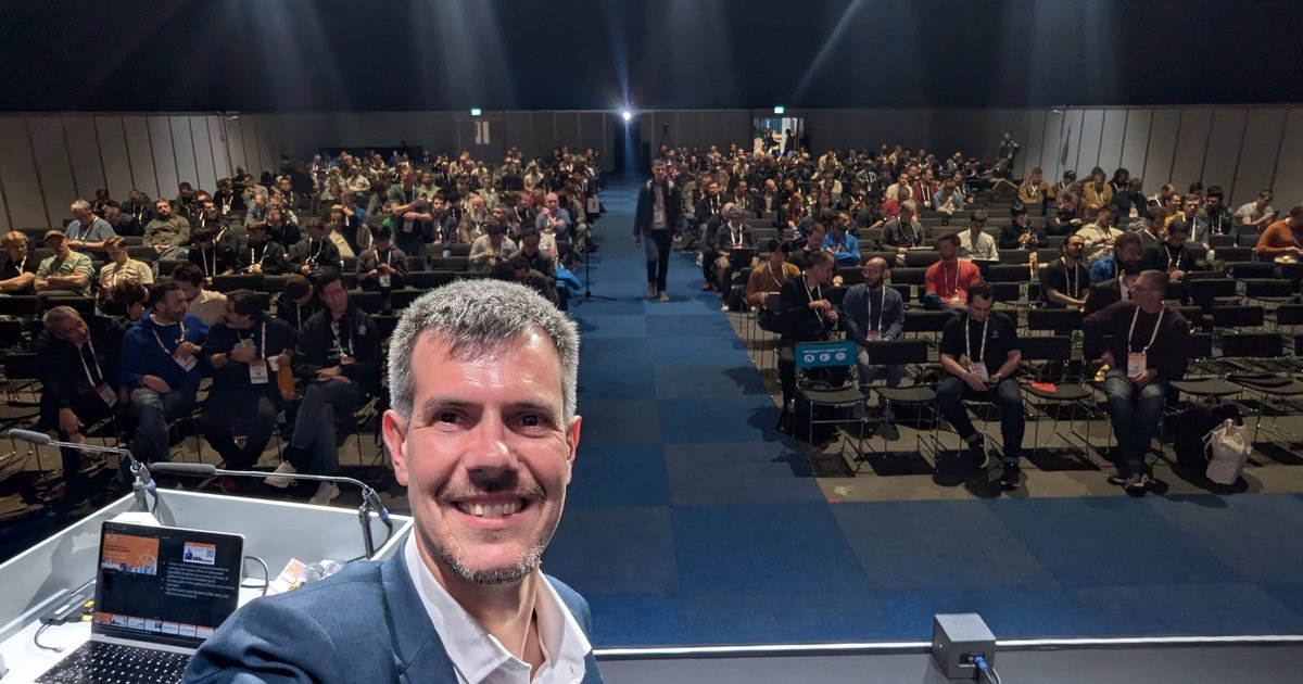 Luca Berton on stage at KubeCon Europe 2026 in Amsterdam minutes before his talk, with the audience filling the hall