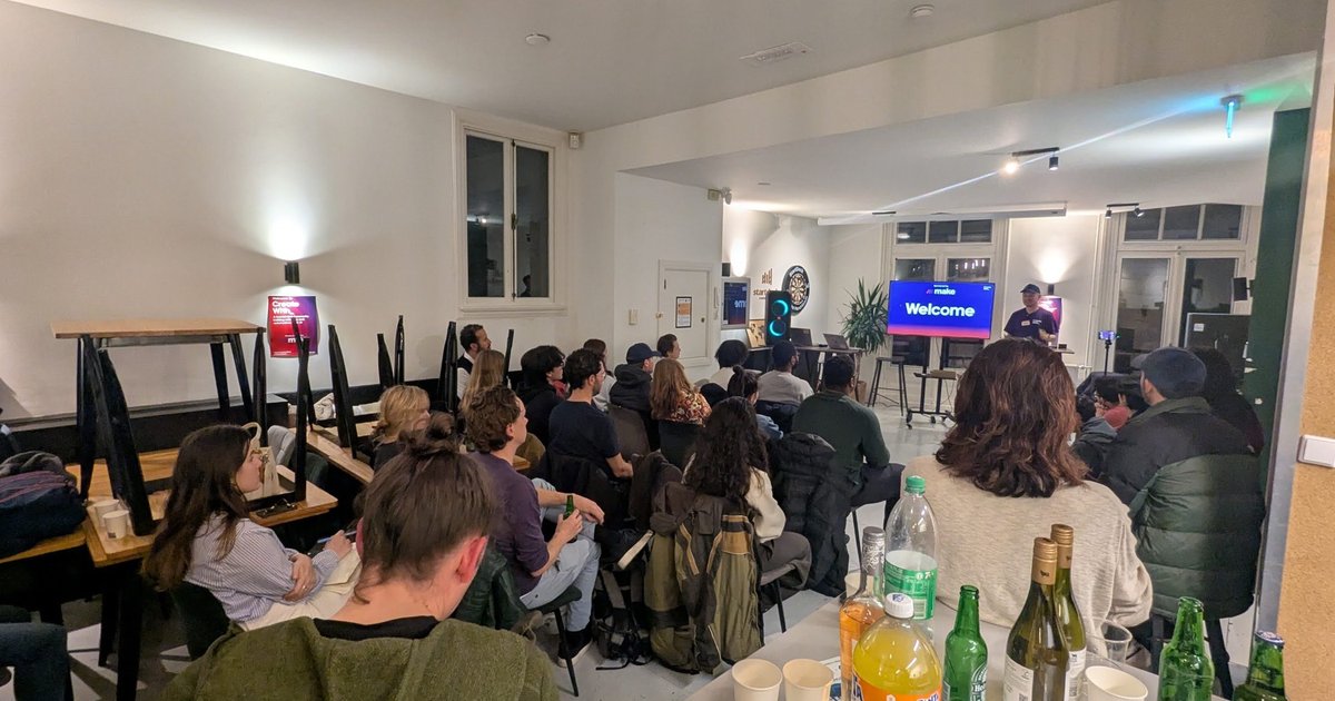 A small room at StartDock Amsterdam with a welcome screen and an audience seated and standing before the talks of a no-code and AI builders evening