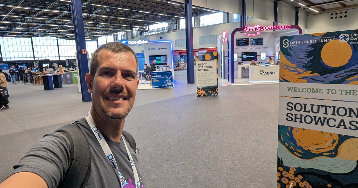 Luca Berton taking a selfie at the entrance of the Open Source Summit Europe 2025 Solutions Showcase at RAI Amsterdam, with the openEuler and AWS open source booths behind him