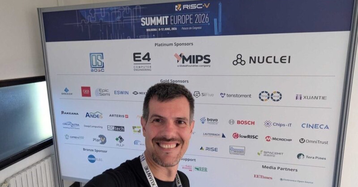 Luca Berton with the RISC-V Summit Europe 2026 sponsor wall in Bologna showing DeepComputing, Epic Semi, ESWIN and other exhibitors