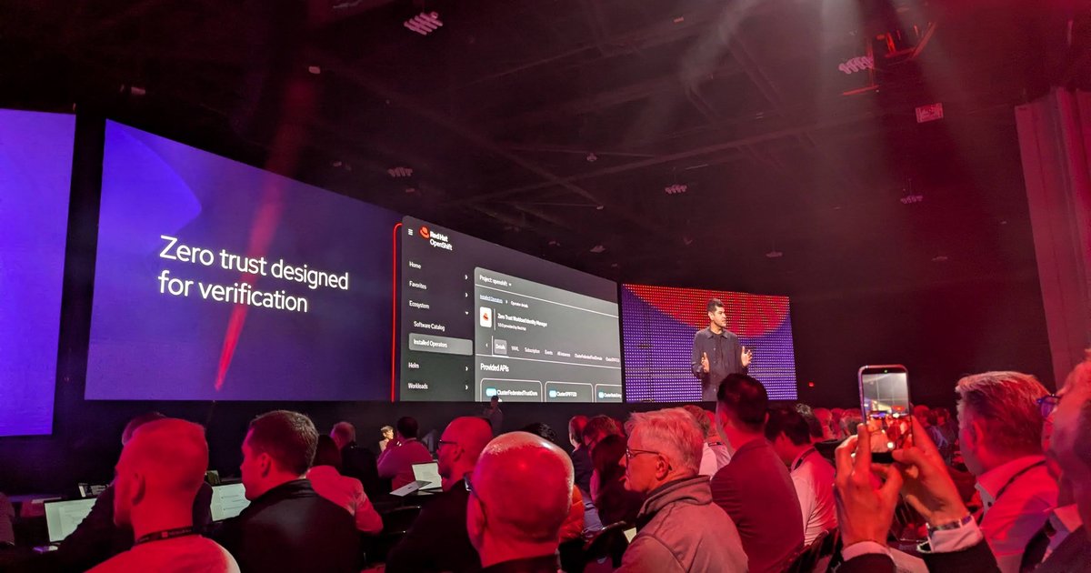A presenter on the Red Hat Summit 2026 keynote stage next to a Zero trust designed for verification slide