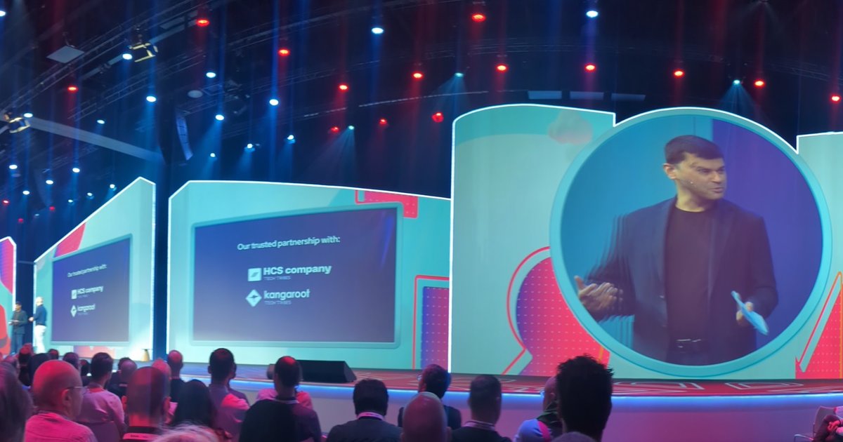 The main stage at Red Hat Summit Connect Utrecht 2025, with a keynote speaker on the video wall and a slide naming HCS company and Kangaroot as partners