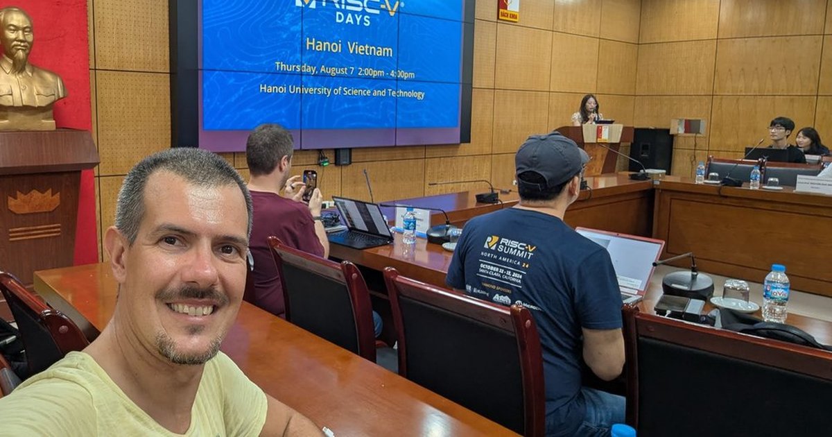 Luca Berton at World RISC-V Days in Hanoi, with the event title slide on the screen behind him
