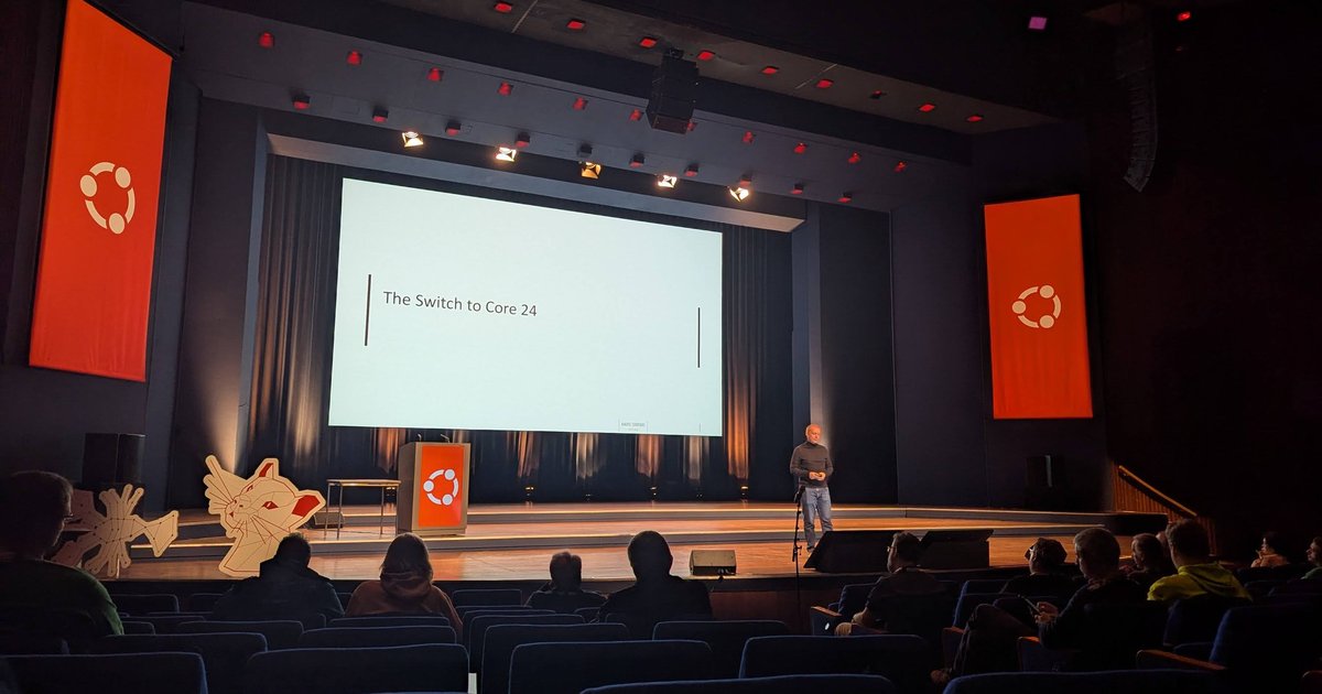 Ubuntu Summit 2024 plenary stage at the World Forum in The Hague, with The Switch to Core 24 on the screen and orange Ubuntu banners